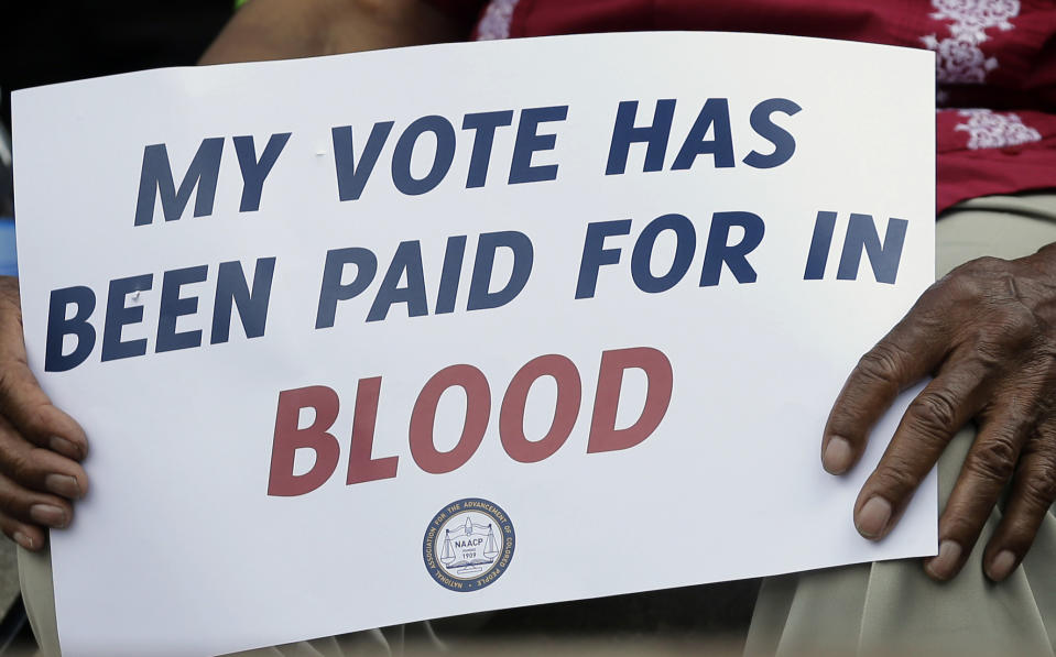 FILE - A man holds a sign as he listens during a rally in Winston-Salem, N.C., July 13, 2015, after the beginning of a federal voting rights trial challenging a 2013 state law. A U.S. Supreme Court decision a decade ago that tossed out the heart of the Voting Rights Act continues to reverberate across the country. Republican-led states continue to pass voting restrictions that, in several cases, would have been subject to federal review had the court left the provision intact. (AP Photo/Chuck Burton, File)