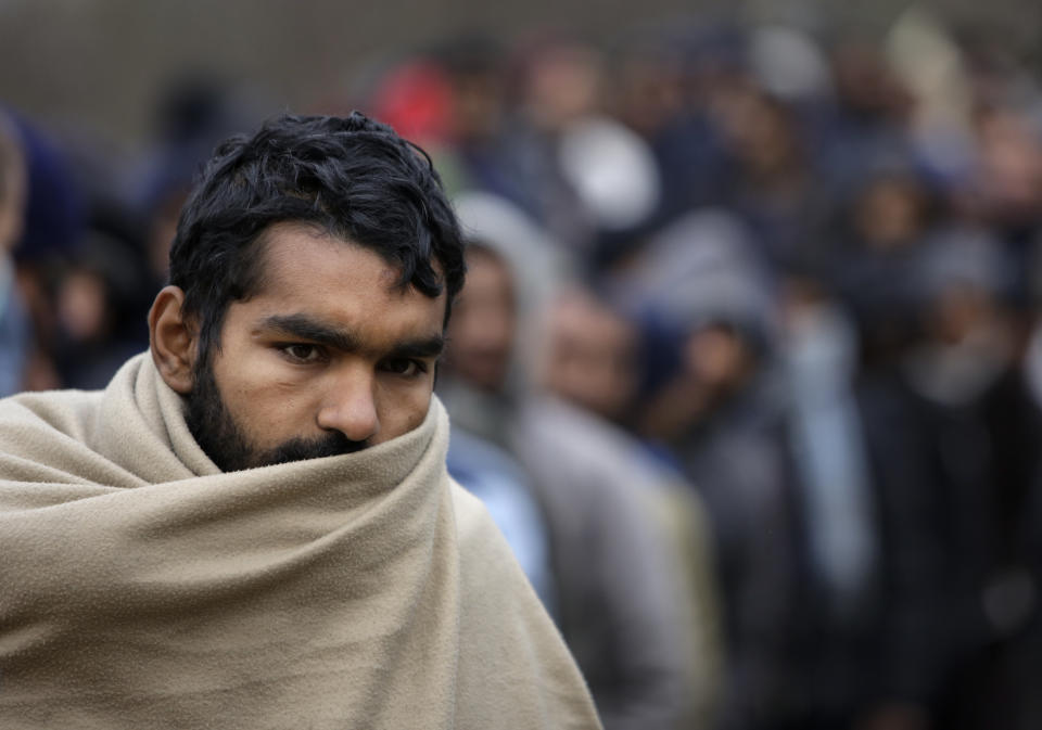 CORRECTING YEAR TO 2018 - In this Sunday Nov. 18, 2018 photo a migrant wrapped in a blanket waits for food distribution at a camp in Velika Kladusa, Bosnia, close to the border to Croatia. The approach of the tough Balkan winter spells tough times for the migrants that remain stuck in the region while trying to reach Western Europe, with hundreds of them staying in make-shift camps with no heating or facilities.(AP Photo/Amel Emric)