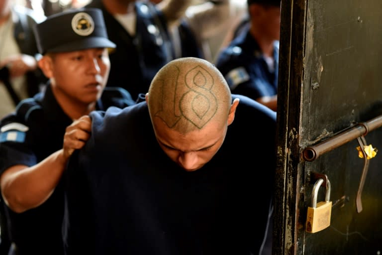 An inmate of the Stage II Male Juvenile Detention Center is escorted as he arrives at a courthouse in Guatemala City on March 21, 2017