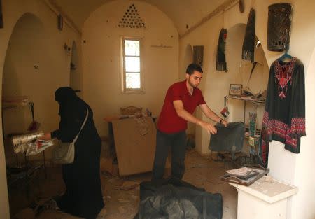 Palestinians retrieve art objects at the arts and handcraft village that was damaged by Israeli air strikes in Gaza City July 15, 2018. REUTERS/Suhaib Salem