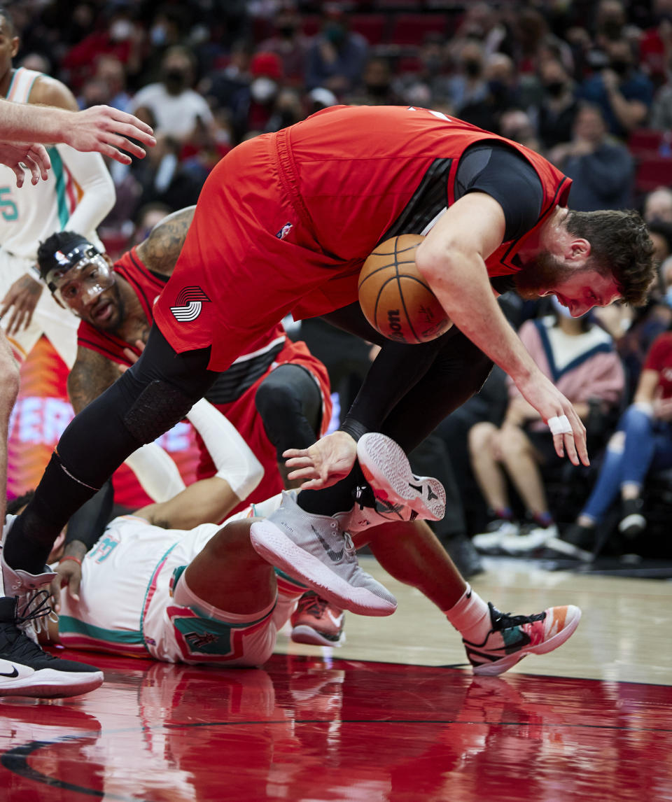 Portland Trail Blazers center Jusuf Nurkic, top, trips over San Antonio Spurs forward Keldon Johnson during the first half of an NBA basketball game in Portland, Ore., Thursday, Dec. 2, 2021. (AP Photo/Craig Mitchelldyer)