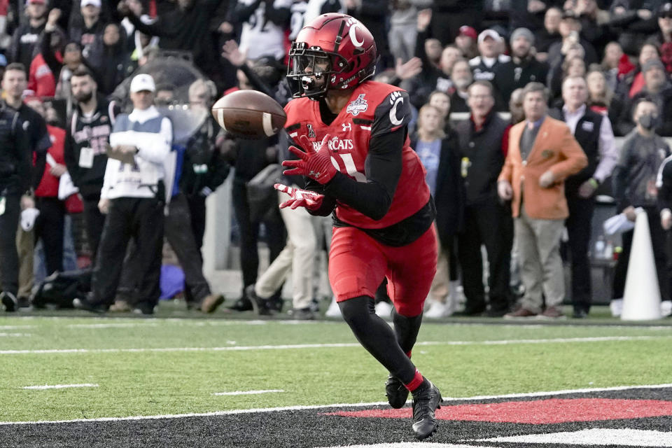 Cincinnati wide receiver Tyler Scott, center, catches a pass for a touchdown during the first half of the American Athletic Conference championship NCAA college football game against Houston Saturday, Dec. 4, 2021, in Cincinnati. (AP Photo/Jeff Dean)