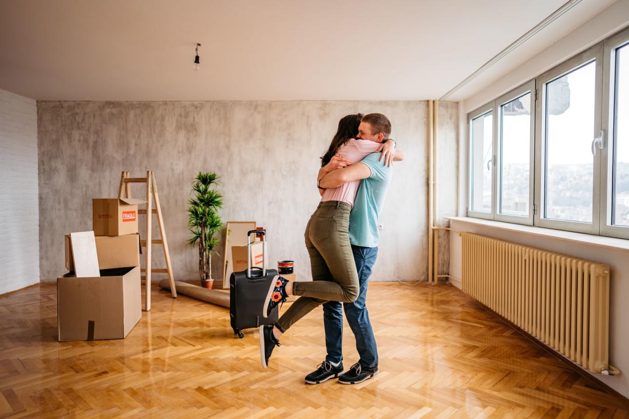 Joyful young couple embracing in their new empty apartment.