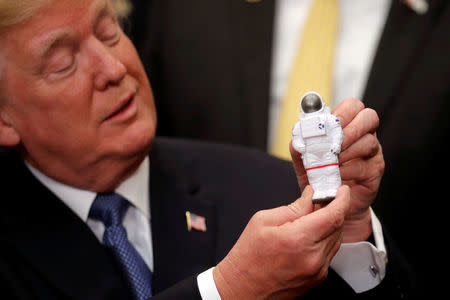 U.S. President Donald Trump holds a space astronaut toy as he participates in a signing ceremony for Space Policy Directive at the White House in Washington D.C., U.S., December 11, 2017. REUTERS/Carlos Barria