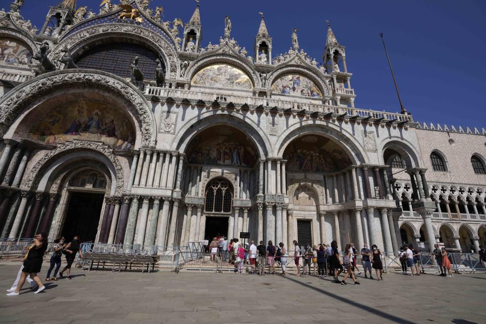 Tourists line up to enter the St.Marks church in Venice, Italy, Thursday, June 17, 2021. Police and traffic warden employees monitor screens showing the flow of people and web cameras at a police station, in Venice, Italy, Thursday, June 17, 2021. After a 15-month pause in mass international travel, Venetians are contemplating how to welcome visitors back to the picture-postcard canals and Byzantine backdrops without suffering the indignities of crowds clogging its narrow alleyways, day-trippers perched on stoops to imbibe a panino and hordes of selfie-takers straining for a spot on the Rialto Bridge or in front of St. Mark's Basilica. (AP Photo/Luca Bruno)(AP Photo/Luca Bruno)