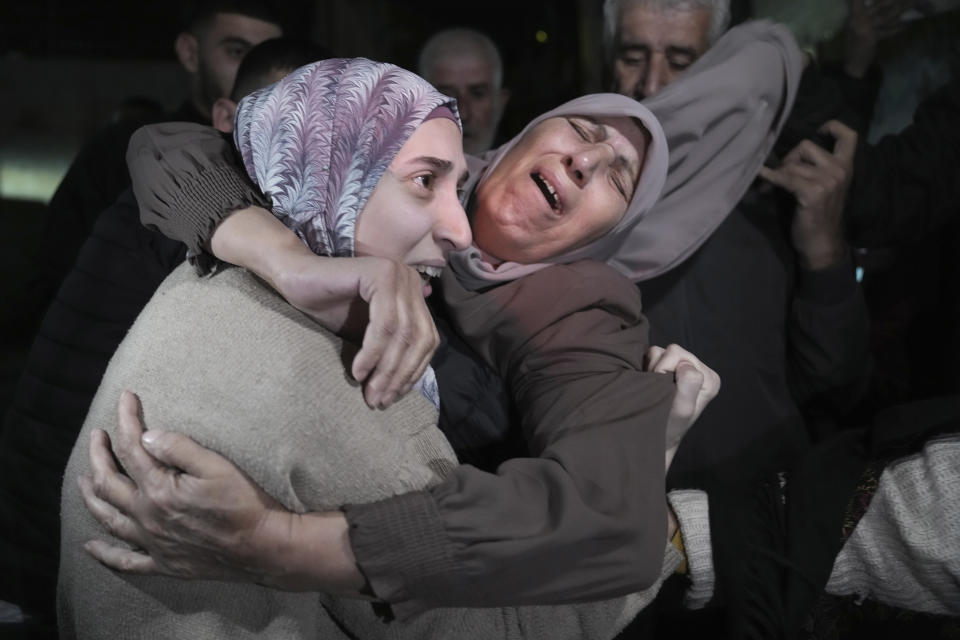 Shuruq Dwayat, left, a Palestinian prisoner released by Israel, is hugged by relatives as she arrives home in the east Jerusalem neighborhood of Sur Bahar, early Sunday Nov. 26, 2023. (AP Photo/Mahmoud Illean)