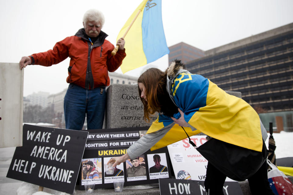 Yulia Kurka, places a candle as Basil Panczak looks on as they demonstrate in support Ukrainian anti-government protesters outside Independence Hall, Wednesday, Feb. 19, 2014, in Philadelphia. The violence on Tuesday was the worst in nearly three months of anti-government protests that have paralyzed Ukraine's capital, Kiev, in a struggle over the identity of a nation divided in loyalties between Russia and the West, and the worst in the country's post-Soviet history. (AP Photo/Matt Rourke)