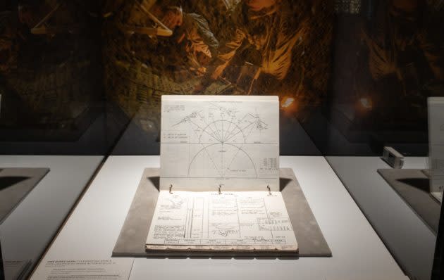 The Apollo 11 Lunar Module Timeline Book sits in a display case at the Living Computers Museum + Labs, with a picture of astronauts Neil Armstrong and Buzz Aldrin in the background. (GeekWire Photo / Kevin Lisota)