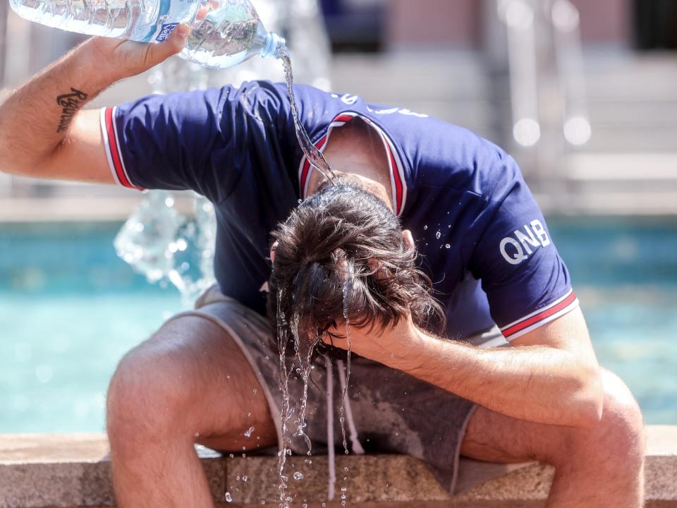 A person pours water on their head during a heatwave.