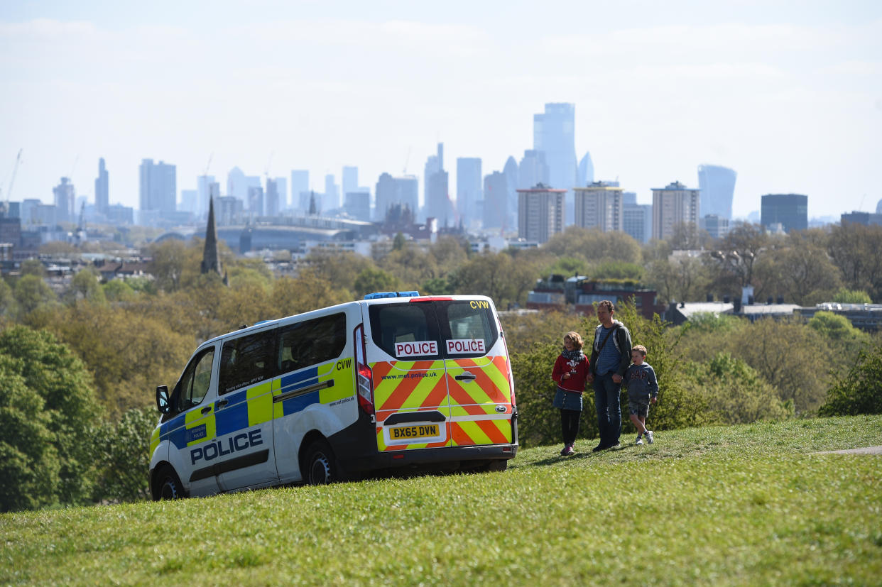 Police pass a family out walking on Primrose Hill, London, as the UK continues in lockdown to help curb the spread of the coronavirus.