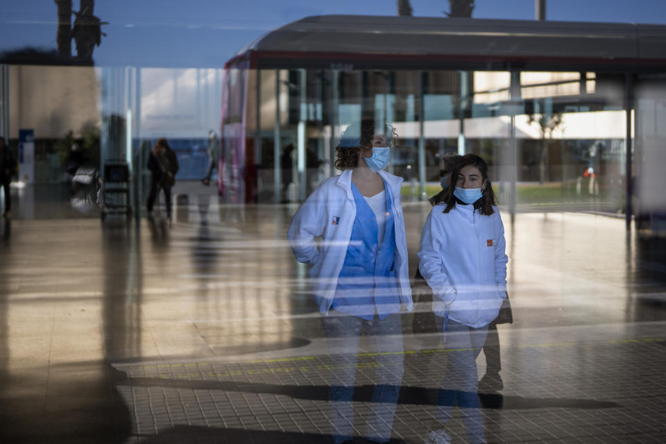 People wearing face masks as a precaution walk inside a hospital in Barcelona, Spain, Monday, Jan. 8, 2024. Regional and national health chiefs are meeting Monday to decide whether to extend mandatory mask—wearing to all health facilities following an epidemic outbreak of flu and other respiratory viruses that are putting a strain on the system. (AP Photo/Emilio Morenatti)