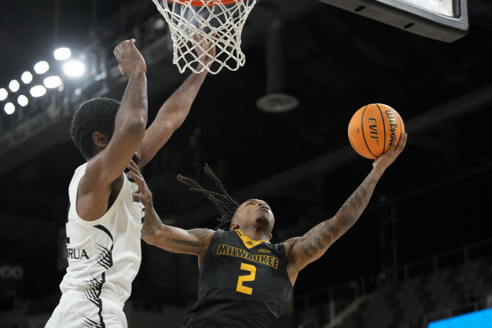 Milwaukee guard Elijah Jamison (2) shoots around Oakland forward Tuburu Naivalurua (12) during the second half of an NCAA college basketball game for the championship of the Horizon League men's tournament in Indianapolis, Tuesday, March 12, 2024. (AP Photo/AJ Mast)