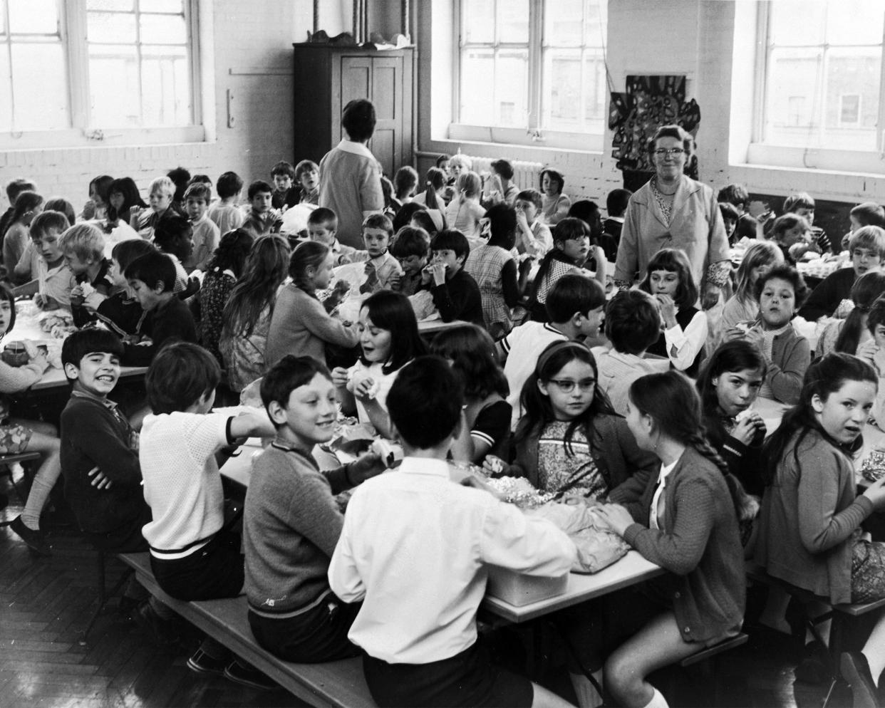 Schoolchildren eating sandwiches in the dining hall at Rotherfield Junior School