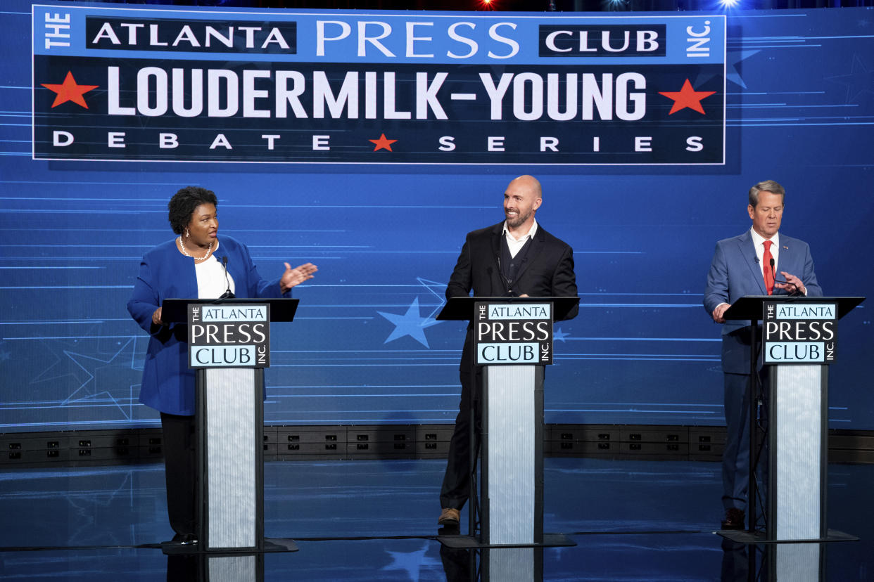 Stacey Abrams, Shane Hazel and Gov. Brian Kemp stand at podiums onstage in front of a backdrop that reads: The Atlanta Press Club Inc. Loudermilk-Young Debate Series.