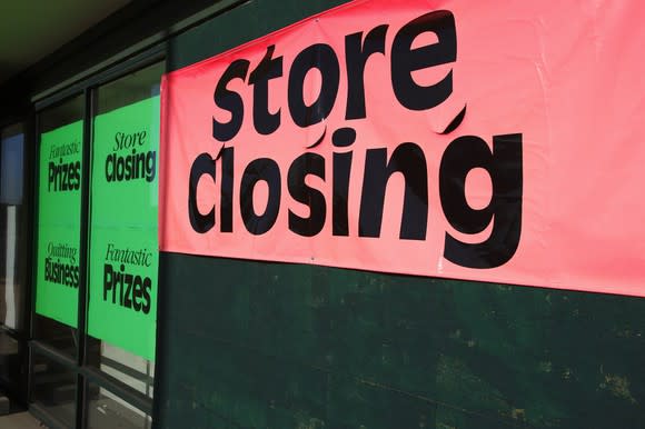 Green and red store closing signs on storefront.