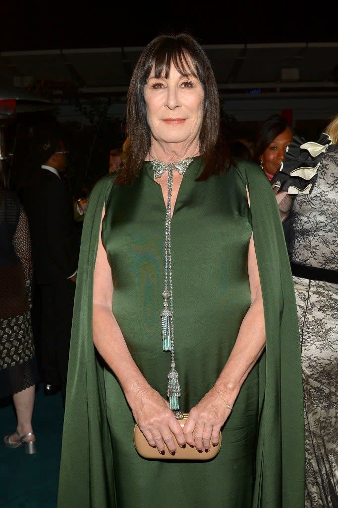 Anjelica Huston in a cape dress with a long tassel necklace at an event