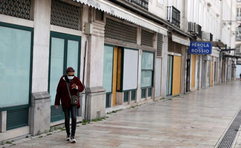 FILE PHOTO: A woman wearing a protective mask as a preventive measure against coronavirus disease (COVID-19) walks at Rossio Square in downtown Lisbon