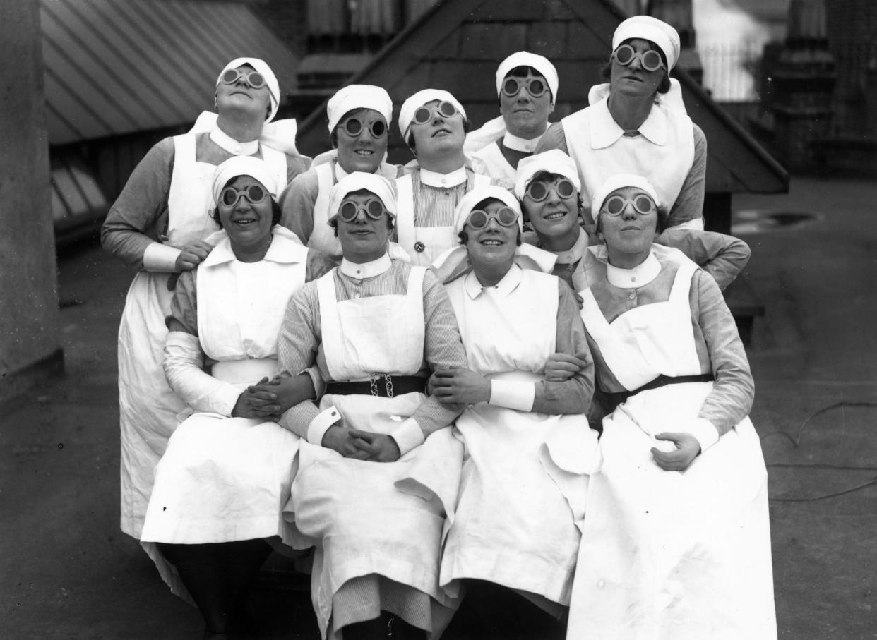 1927: Nurses observe a solar eclipse through special dark glasses in England. 