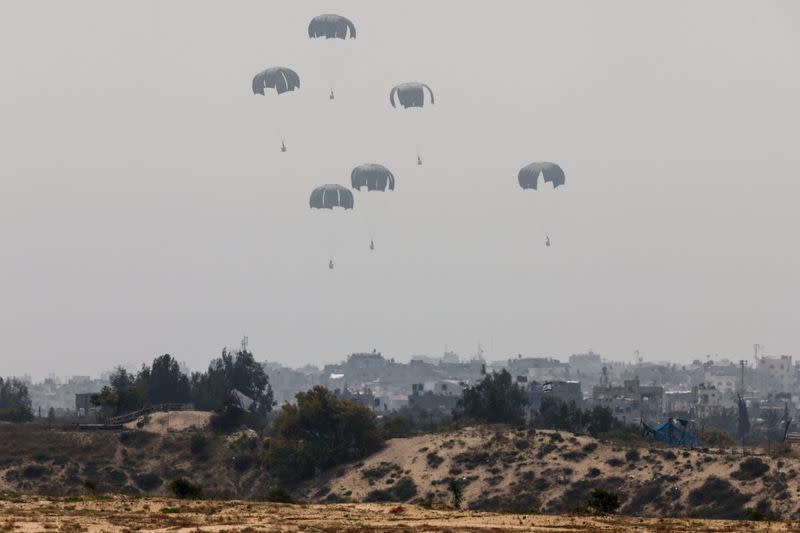 La ayuda humanitaria cae hacia la Franja de Gaza después de ser lanzada desde un avión, en medio del conflicto en curso entre Israel y el grupo islamista palestino Hamás, vista desde Israel,