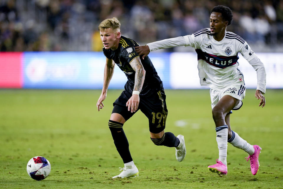 Los Angeles FC midfielder Mateusz Bogusz, left, and Vancouver Whitecaps forward Ali Ahmed vie for the ball during the second half of an MLS playoff soccer match Saturday, Oct. 28, 2023, in Los Angeles. (AP Photo/Ryan Sun)