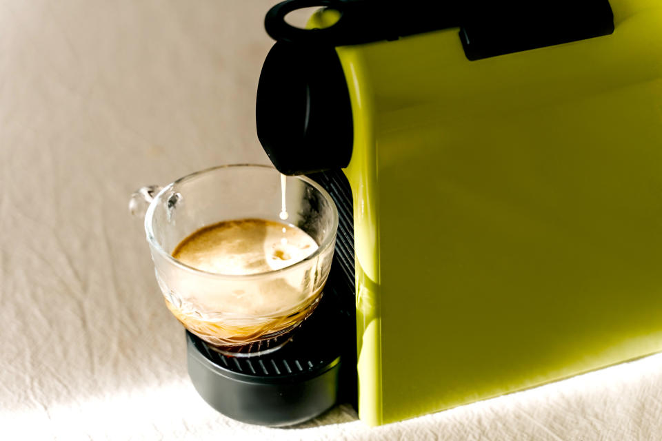 Espresso being made in a green machine, coffee dripping into a glass cup