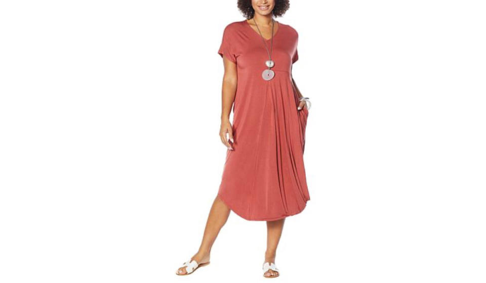 Woman wearing rust colored drapey dress with pockets