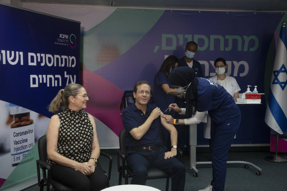 Israeli President Isaac Herzog receives a third coronavirus vaccine injection while his wife, Michal, left, reacts, at the Sheba Medical Center in Ramat Gan, Israel, Friday, July 30, 2021. (AP Photo/Maya Alleruzzo, Pool)