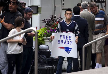 A supporter of New England Patriots quarterback Tom Brady holds a sign as he stands with a large crowd of media outside the National Football League (NFL) headquarters offices in Manhattan, New York City, June 23, 2015. REUTERS/Mike Segar