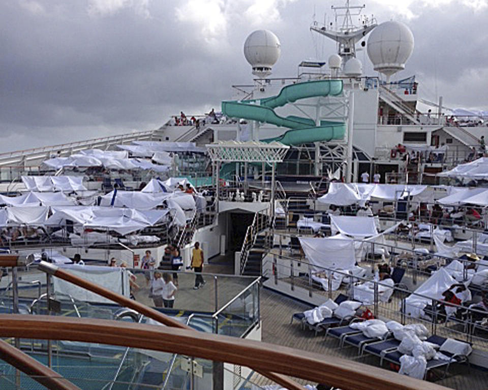 FILE - This Feb. 10, 2013 file photo provided by Kalin Hill, of Houston, shows passengers with makeshift tents on the the deck of the Carnival Triumph cruise ship at sea in the Gulf of Mexico. About three dozen passengers aboard the ill-fated cruise liner have filed a lawsuit in Miami hoping to collect thousands of dollars as a result of lingering medical and mental issues they claim were caused by their nightmarish experience. (AP Photo/Kalin Hill, File)