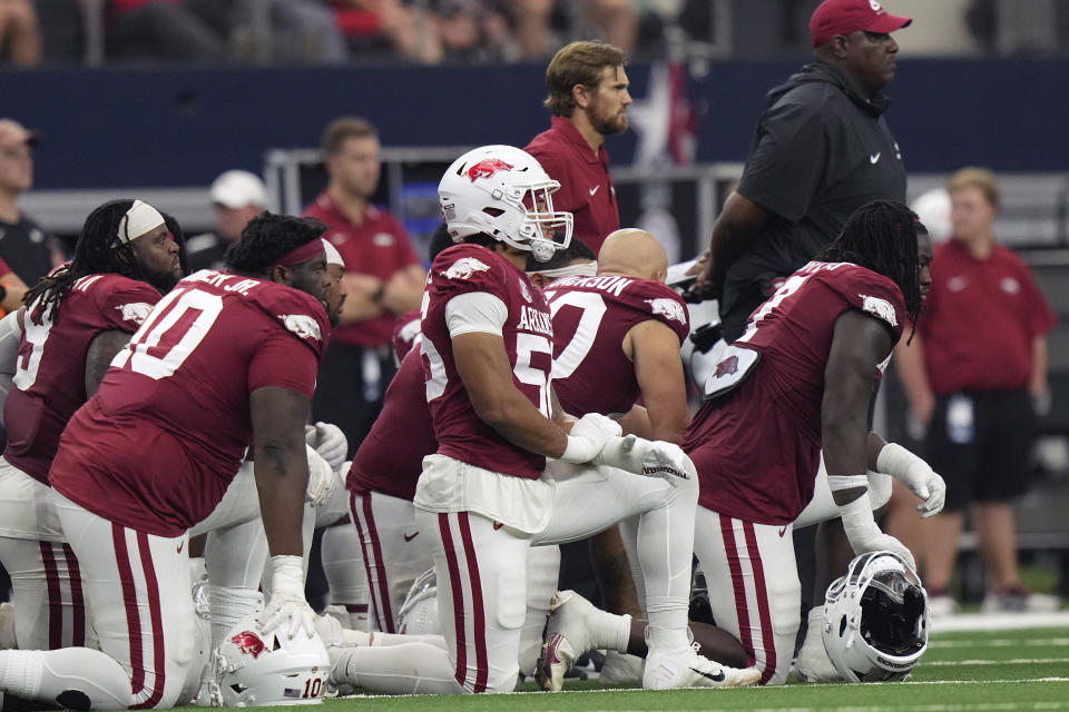 Arkansas players kneel as defensive lineman John Morgan III is worked on after he collapsed during the second half of an NCAA college football game against Texas A&M Saturday, Sept. 30, 2023, in Arlington, Texas. (AP Photo/LM Otero)