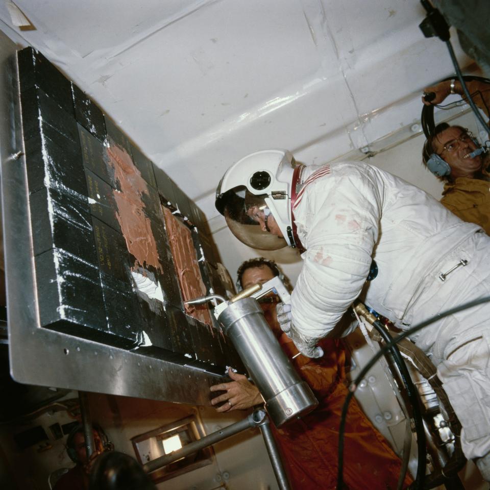 American astronaut Anna Lee Fisher services a 'damaged' tile during a simulation of repair work during EVA (Extravehicular Activity) in the weightless environment of a Boeing KC-135 Stratotanker (aka the 'Vomit Comet'), 3rd July 1980. The aircraft flies in a series of parabolic curves in order to simulate microgravity for short periods. The tool she is using is part of the thermal protection system (TPS) repair kit supplied in case of issues prior to re-entry.