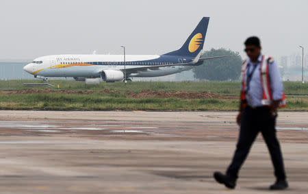 A Jet Airways Boeing 737-800 passenger plane moves on the runway as a man walks past at an airport in New Delhi, August 27, 2018. REUTERS/Adnan Abidi/Files