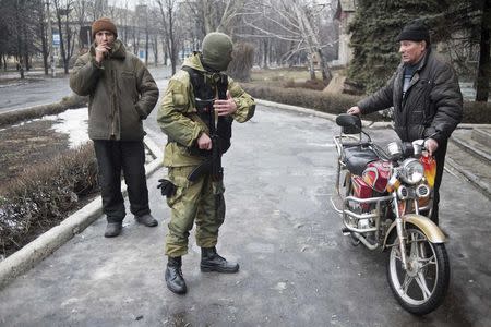A member of the Ukrainian armed forces offers local residents to join people who are boarding a bus and fleeing from military conflict in Debaltseve, February 3, 2015. REUTERS/Sergey Polezhaka