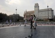 FILE PHOTO: Women wear protective face masks as they walk through an empty Plaza de Catalunya (Catalonia Square), amidst concerns over coronavirus outbreak, in Barcelona