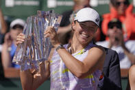 Iga Swiatek, of Poland, smiles as she holds her trophy after defeating Maria Sakkari, of Greece, in the women's singles finals at the BNP Paribas Open tennis tournament Sunday, March 20, 2022, in Indian Wells, Calif. Swiatek won 6-4, 6-1. (AP Photo/Mark J. Terrill)