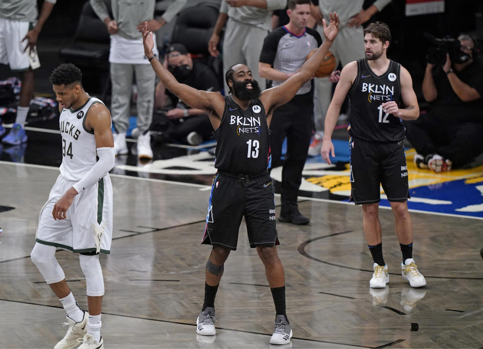 Brooklyn Nets guard James Harden (13) encourages the crowd to get behind the team during the final minutes of Game 5 of a second-round NBA basketball playoff series against the Milwaukee Bucks, Tuesday, June 15, 2021, in New York. Bucks forward Giannis Antetokounmpo (34) walks away. Nets forward Joe Harris is at right. The Nets won 114-108 to take a 3-2 lead in the series. (AP Photo/Kathy Willens)