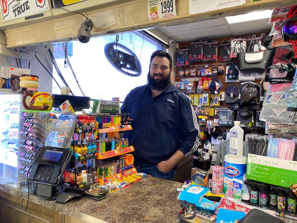 a man poses behind the cash register at a gas station