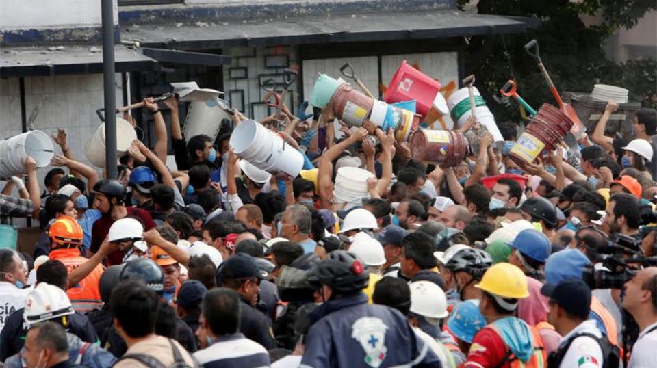 Volunteers relay buckets filled with debris away from the school. Source: AP