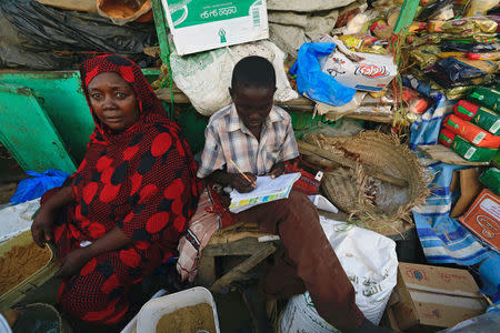 A student does his homework near his mother in Nyala market, during Sudanese President Omar al-Bashir visit to the war-torn Darfur region, in Nyala, Darfur, Sudan September 19, 2017. REUTERS/Mohamed Nureldin Abdallah