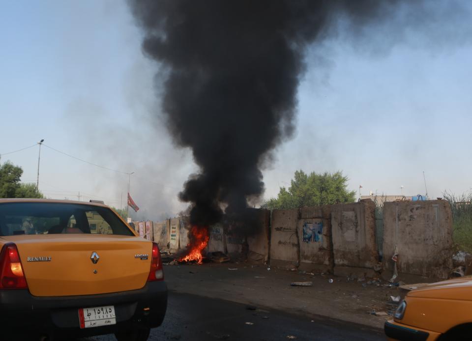 Motorists pass by a fire lit by anti-government protesters in Baghdad, Iraq, Sunday, Oct. 6, 2019. The spontaneous protests which started Tuesday in Baghdad and southern cities were sparked by endemic corruption and lack of jobs. Security forces responded with a harsh crackdown, with dozens killed. (AP Photo/Khalid Mohammed)