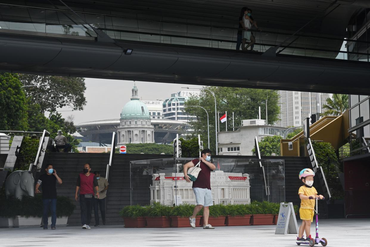 People wearing face masks walk around the Marina Bay in Singapore on Oct. 13, 2021. (Photo by Then Chih Wey/Xinhua via Getty Images)