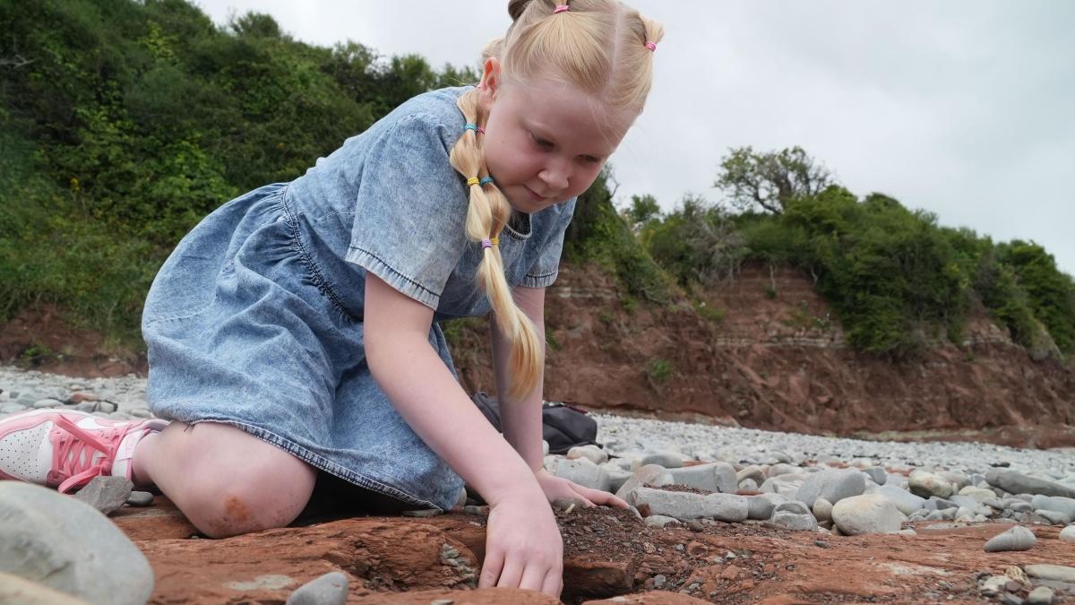 Dziewczyna spacerując po plaży odkrywa ślady dinozaurów