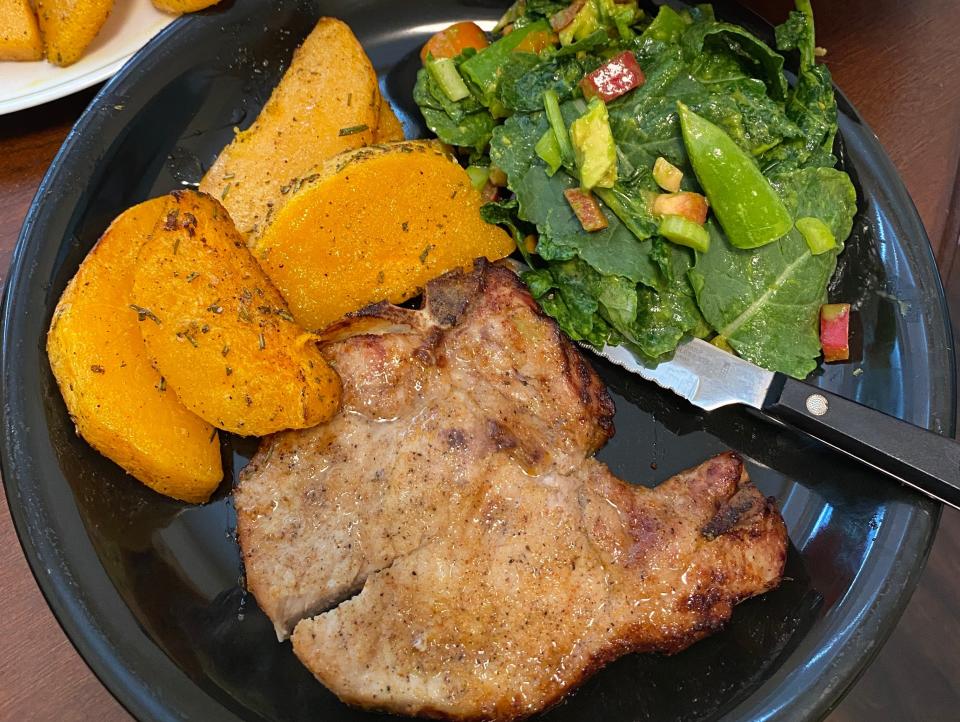 pork chops, salad, and butternut squash on a dinner plate