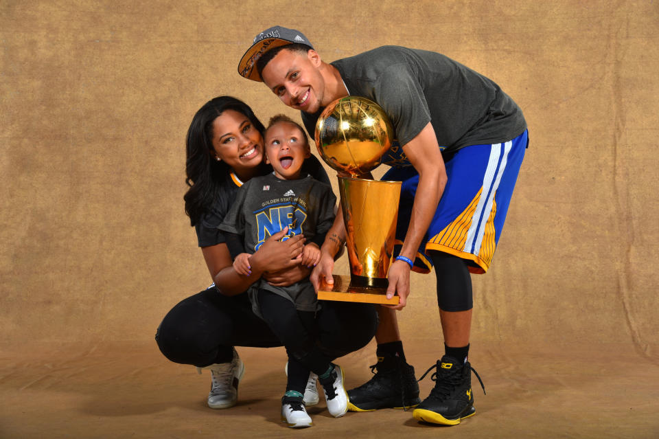 CLEVELAND, OH - JUNE 16: Ayesha Curry, Riley Curry and Stephen Curry #30 of the Golden State Warriors poses for a portrait with the Larry O'Brien trophy after defeating the Cleveland Cavaliers in Game Six of the 2015 NBA Finals on June 16, 2015 at Quicken Loans Arena in Cleveland, Ohio.&nbsp;