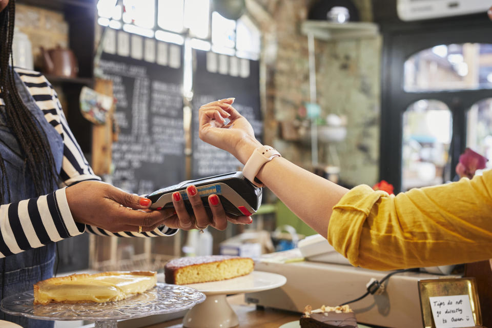 Young woman paying for goods with a smart watch in a coffee shop.