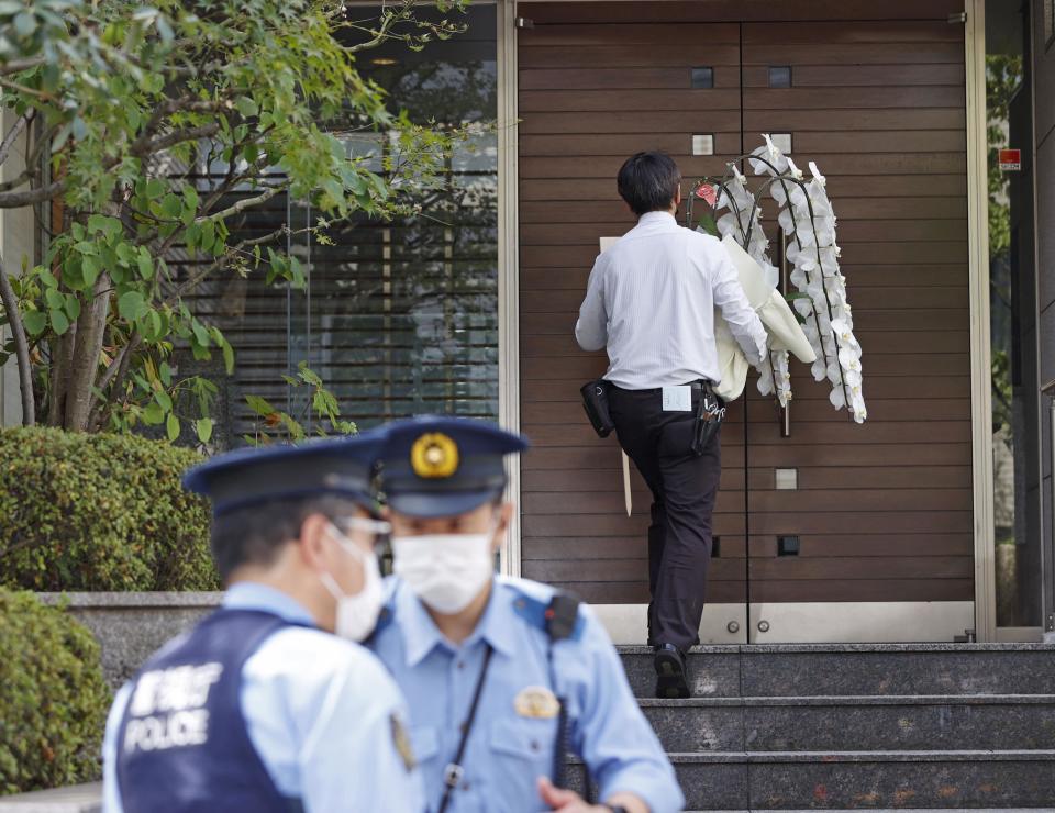 A worker brings a condolence flower to the residence of Japan's former Prime Minister Shinzo Abe who was assassinated Saturday, July 9, 2022, in Tokyo. The body of Japan’s former Prime Minister Shinzo Abe was returned to Tokyo on Saturday after he was fatally shot during a campaign speech in western Japan a day earlier.(Kyodo News via AP)