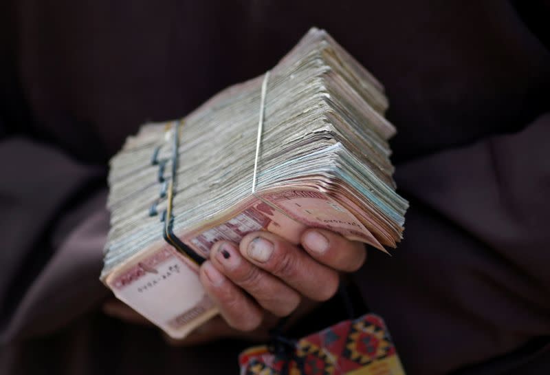 FILE PHOTO: Money changer holds a stack of Afghan currency on a street in central Kabul