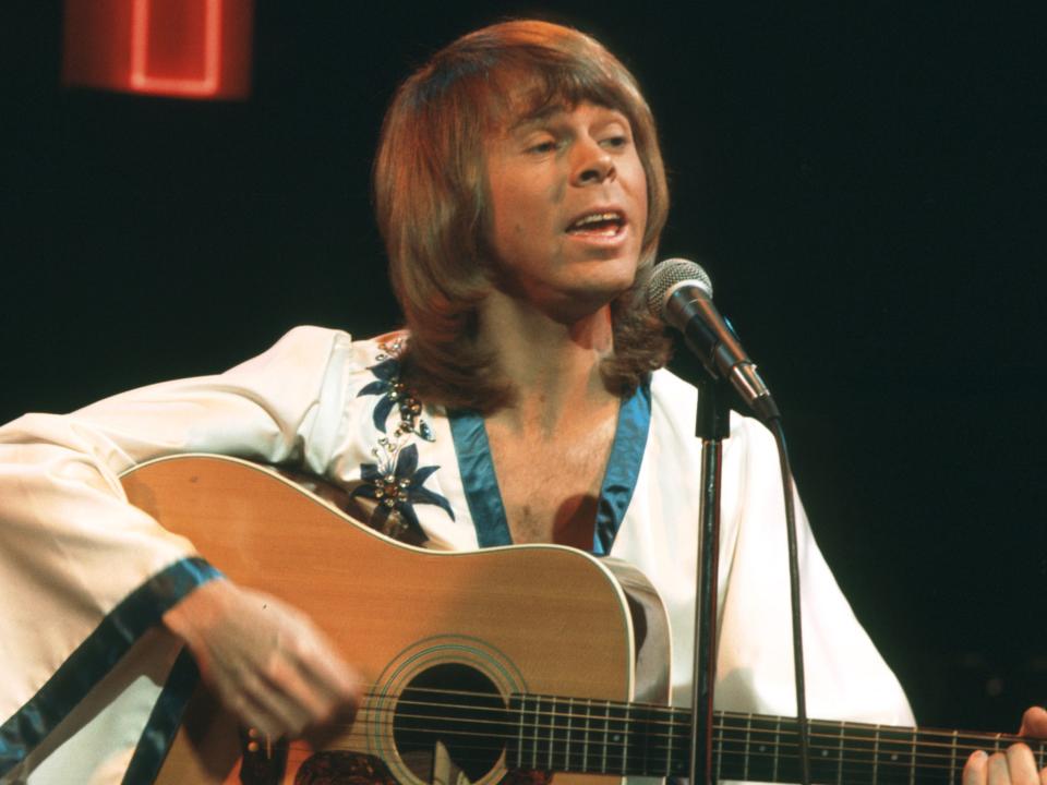 Bjorn Ulvaeus of ABBA playing guitar and singing.