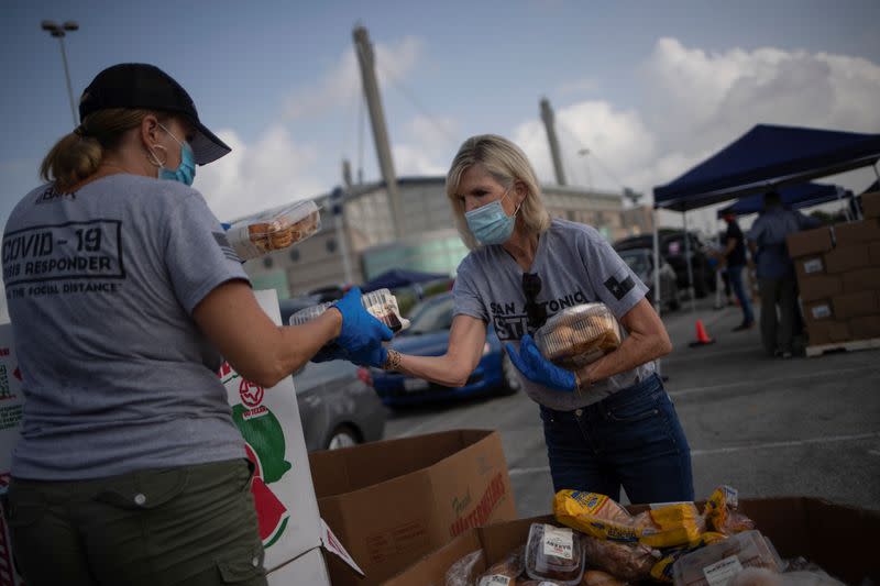 Volunteers give food to residents economically affected by COVID 19 pandemic during San Antonio Food Bank distribution in Texas