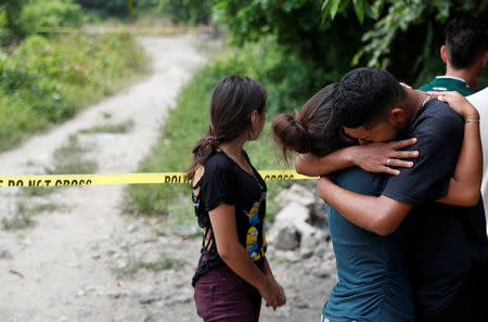 The friends of two men who were killed in gang violence cry at the crime scene in San Pedro Sula, Honduras, July 24, 2018. REUTERS/Goran Tomasevic